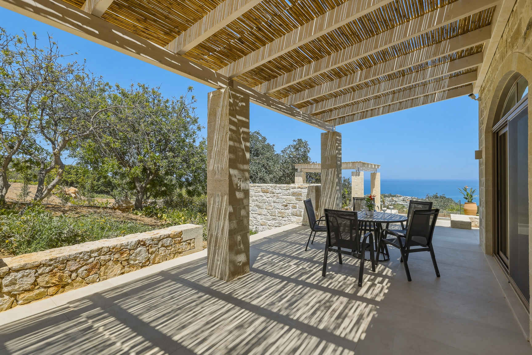 Überdachte Terrasse unter der Pergola mit Esstisch und Meerblick