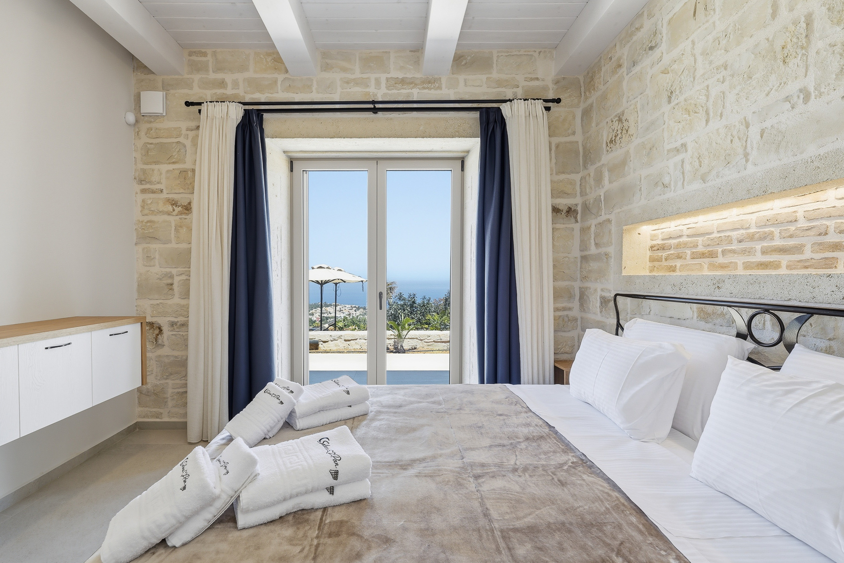 Schlafzimmer mit Natursteinwänden und direktem Meerblick