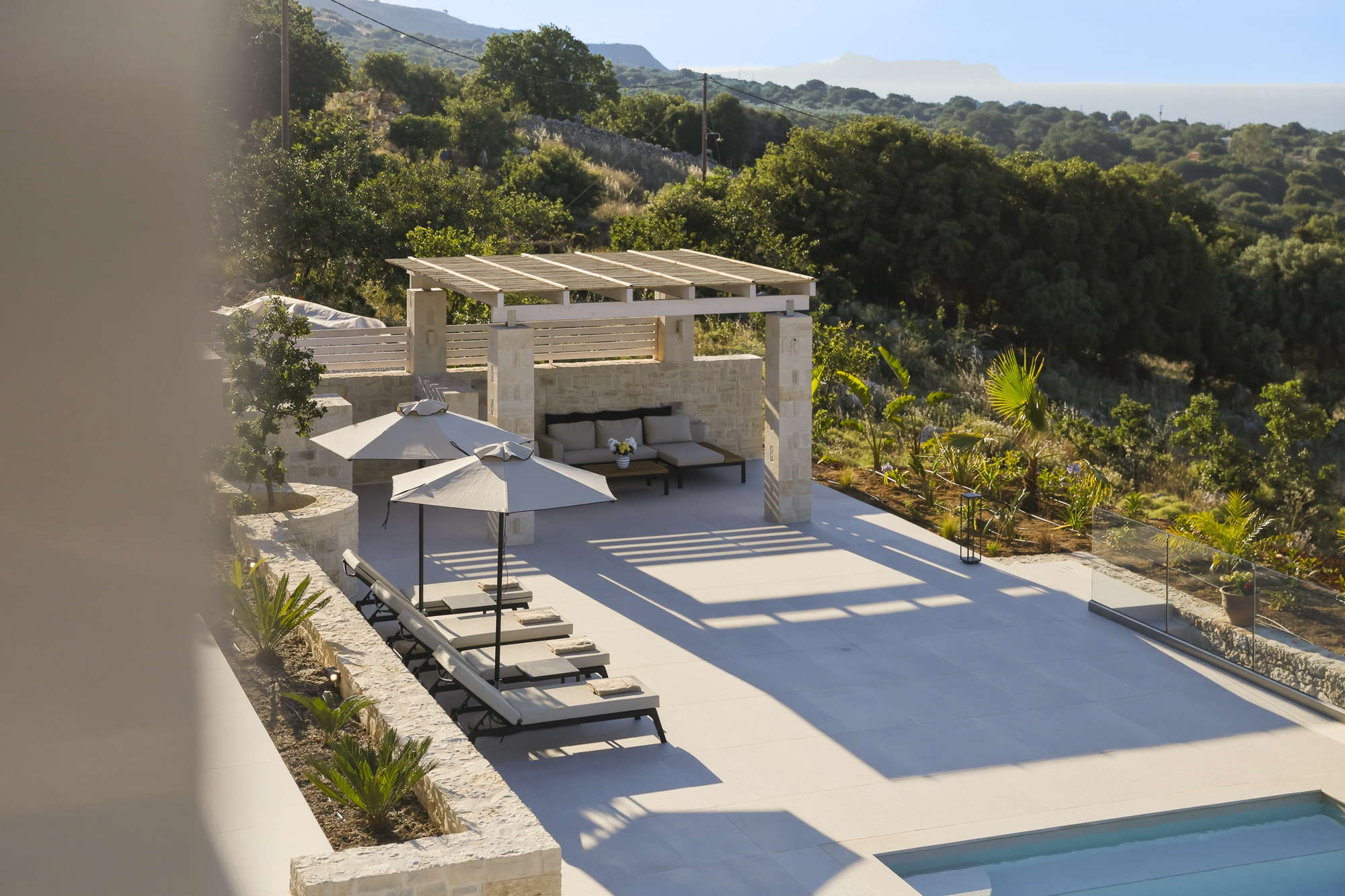 Pooldeck der Villa Pan mit Pergola, Sonnenliegen und Blick in die kretische Berglandschaft