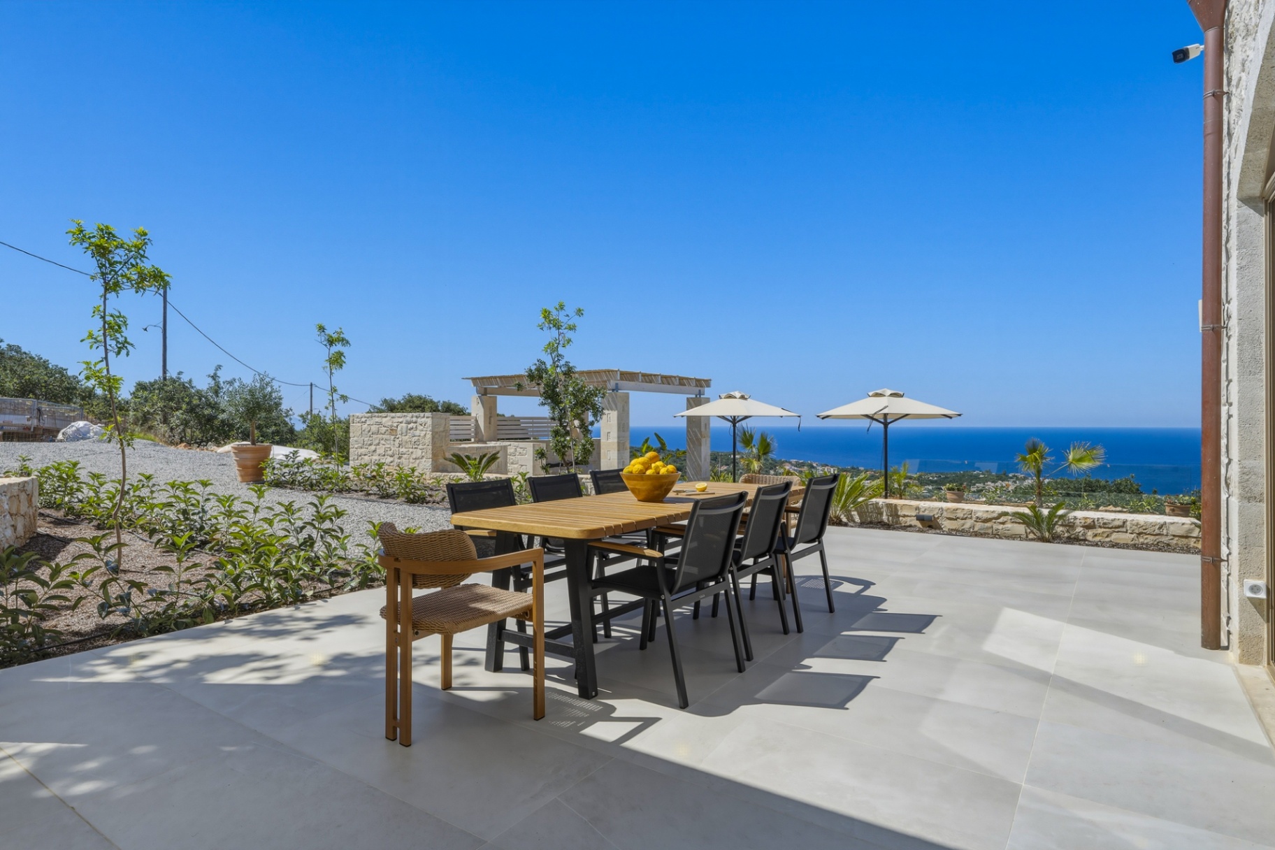 Esstisch draußen mit weitem Blick aufs Meer und Sonnenschirmen